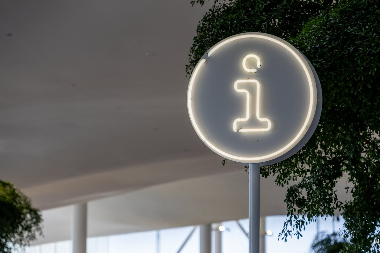 Modern info sign at Helsinki library with minimalist design and foliage.