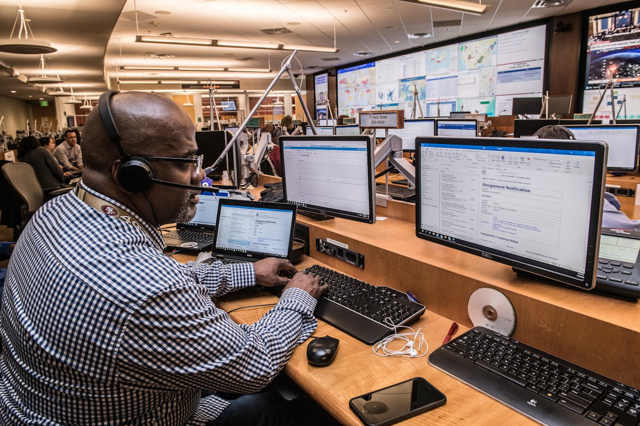 Focused man in office working on computers, engaged in technical research and communication.