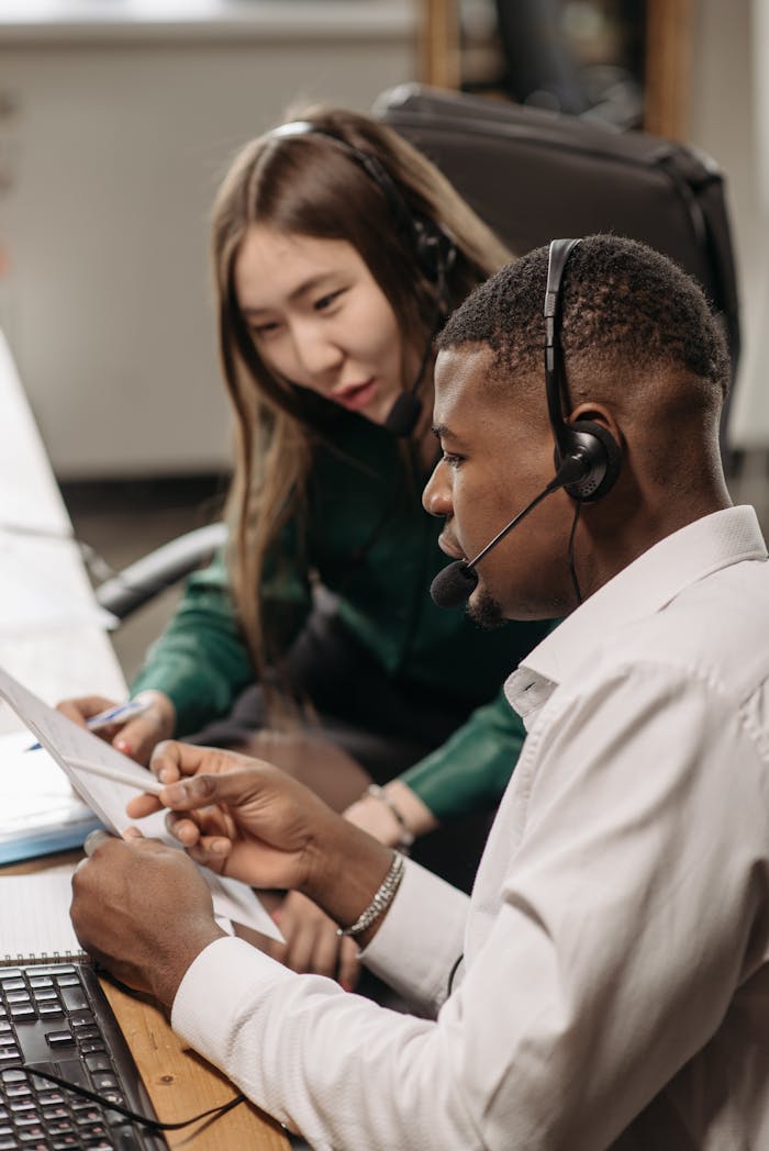 Two colleagues working together with headsets in an office setting.